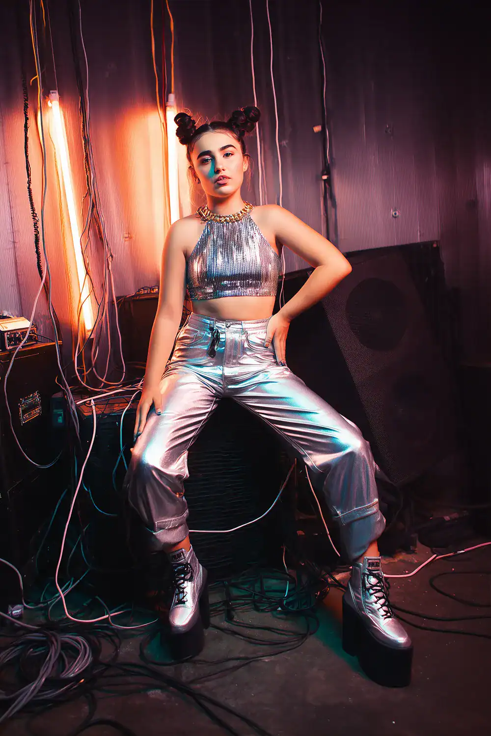 Frau in silbernem Metallic-Top und Hose mit Plateauschuhen und Space Buns – 90er Popstar Halloween-Kostüm für Frauen