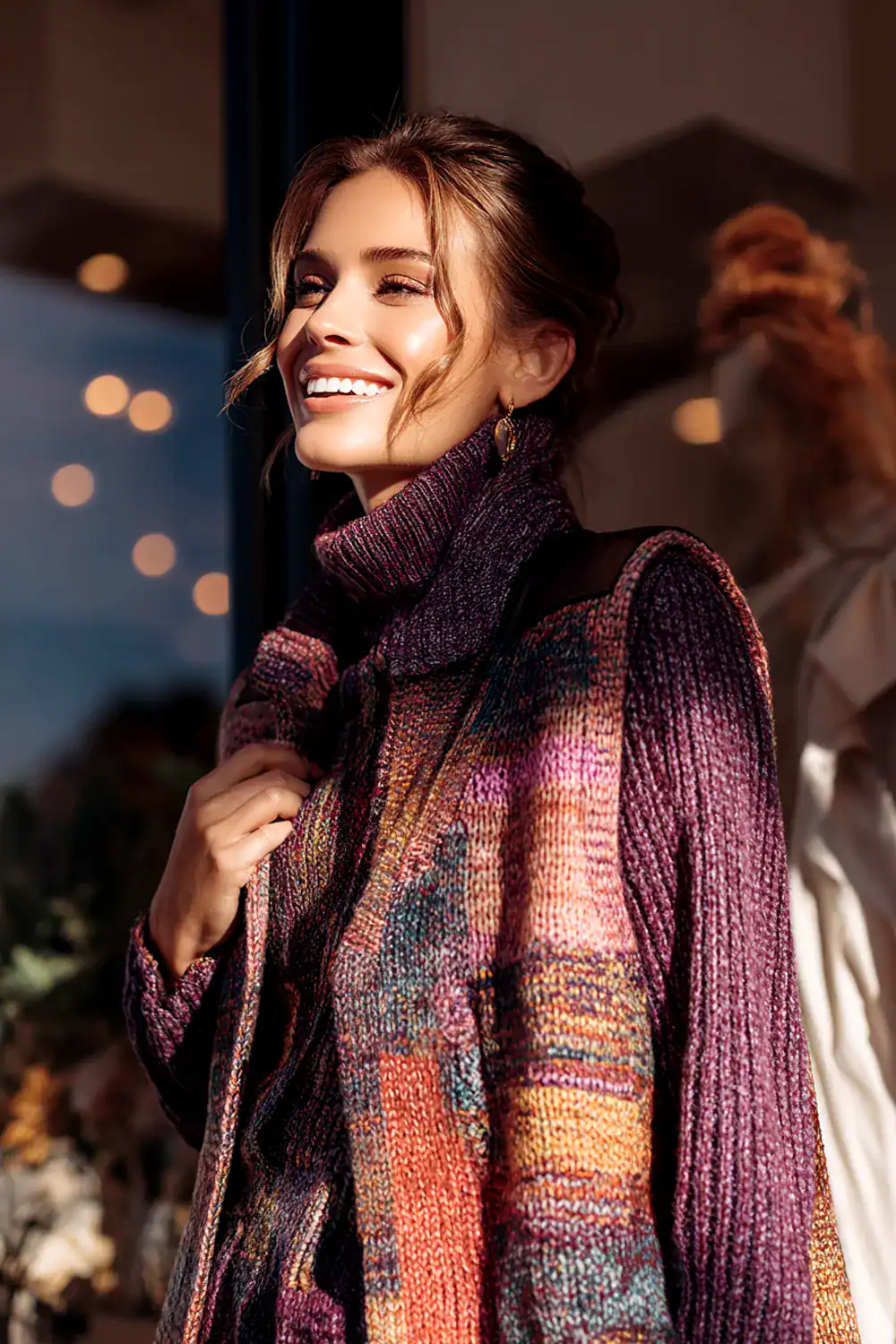 Frau im bunten Strickpullover mit Rollkragen im modernen Winter-Streetstyle, lächelnd in der Sonne